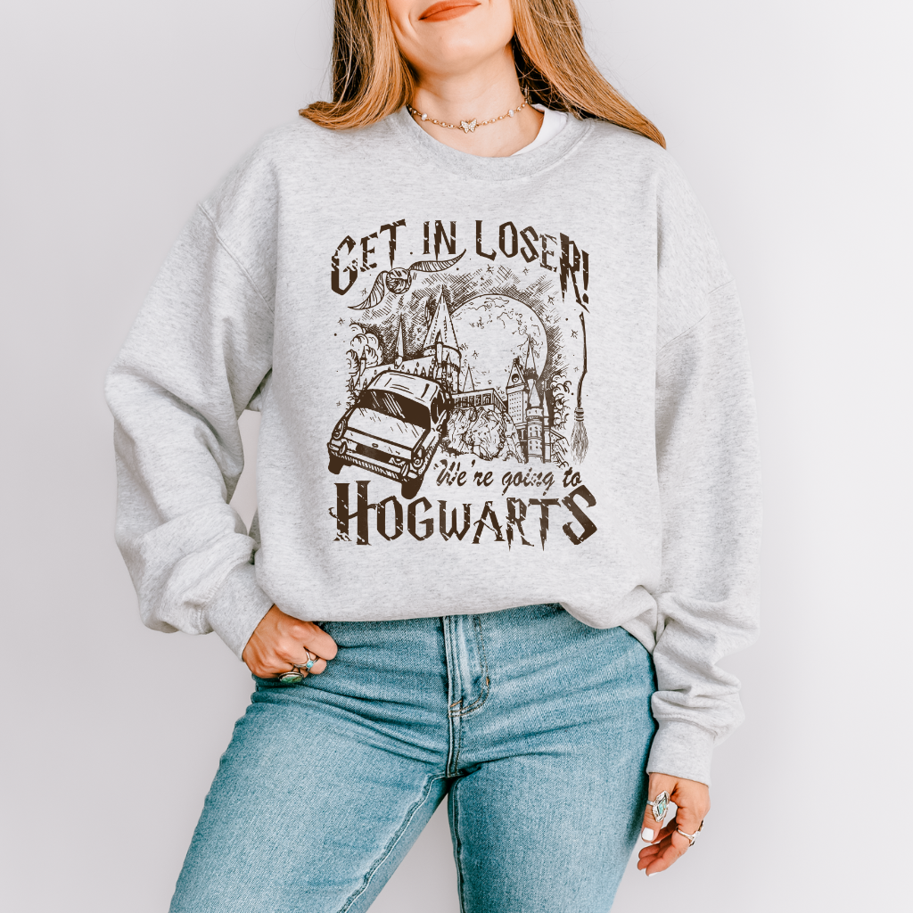 The phrase "Get in Loser, we're going to Hogwarts," is displayed in the classic Harry Potter font surrounding an image of the Weasley's flying car flying to Hogwarts. A golden snitch and wizard broom are also in the design.