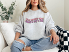 A cozy grey sweatshirt with the words "I'm pretty cool, but I cry a lot," written in a wavy, colorful font, surrounded by several small, yellow stars.